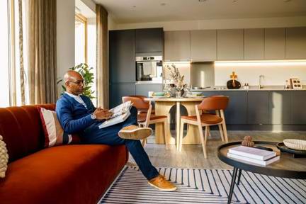 man sat on his sofa and reading a book