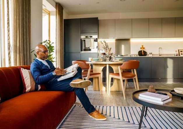 man sat on his sofa and reading a book