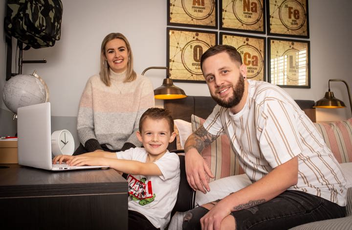 young boy at desk with his parents in their bedroom