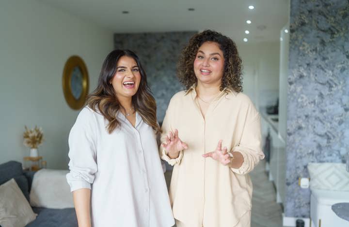 Two women standing in their living-room laughing and chatting