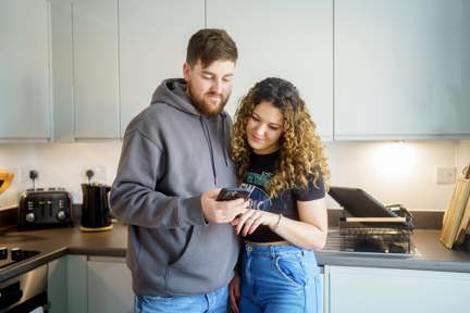couple looking at their phone together in their kitchen