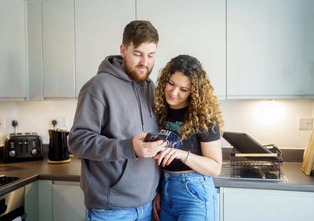 couple looking at their phone together in their kitchen