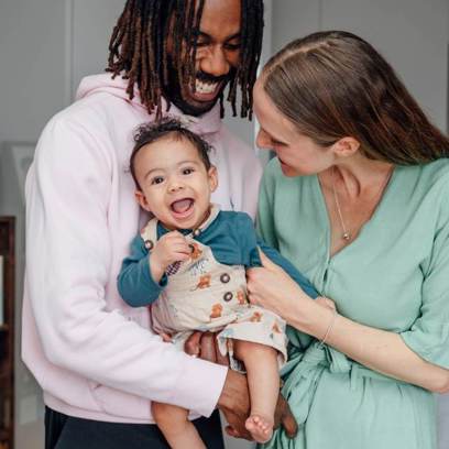 couple holding and smiling with baby in their kitchen