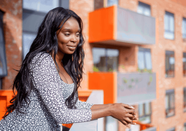 A woman leaning over a balcony of her Shared Ownership home