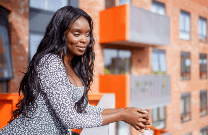 A woman leaning over a balcony of her Shared Ownership home