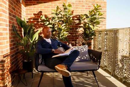 man reading a book while sat on his balcony