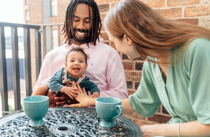 Couple sat on balcony with their baby